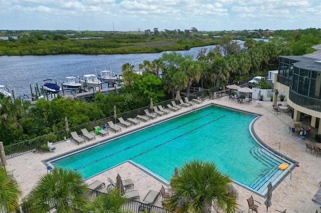 community pool featuring fence, a water view, and a patio