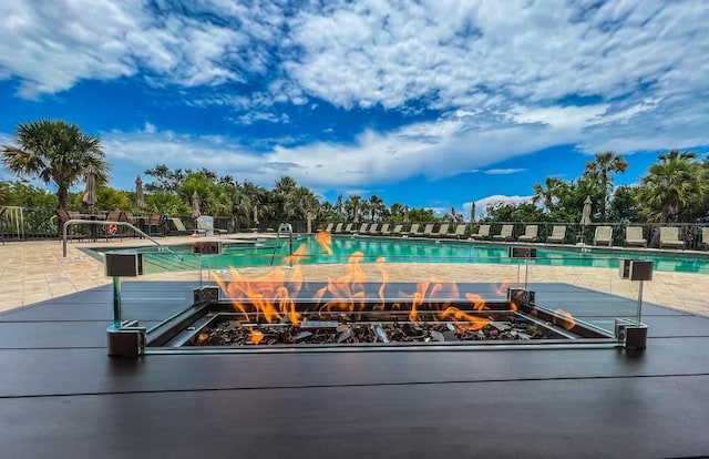 surrounding community featuring a pool, a fire pit, and a patio area