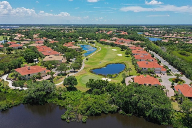 aerial view of property's location featuring nearby suburban area, a large body of water, a golf course, and a tree filled landscape