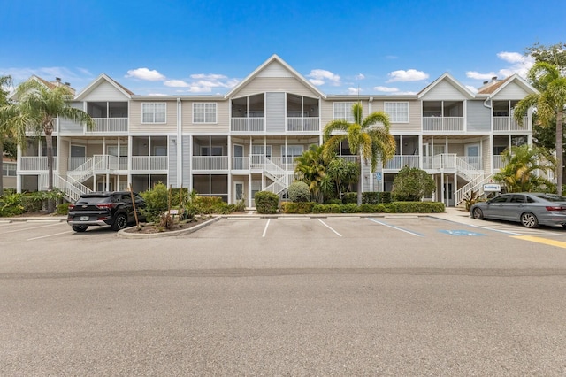 view of apartment building / complex with uncovered parking and stairs