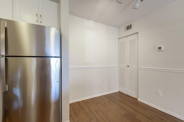 kitchen with freestanding refrigerator, wood finished floors, white cabinets, and baseboards