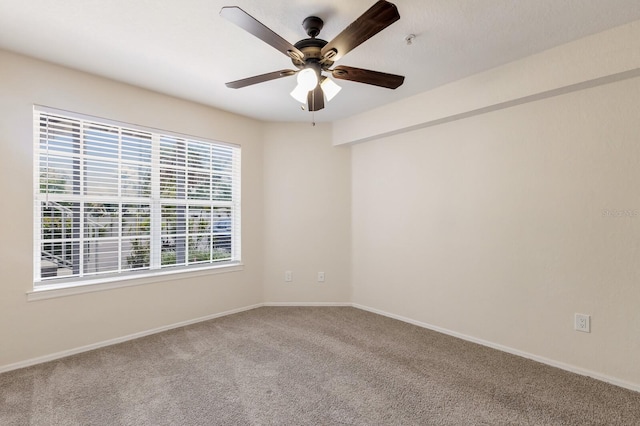 empty room featuring carpet flooring, ceiling fan, baseboards, and fire sprinkler in ceiling