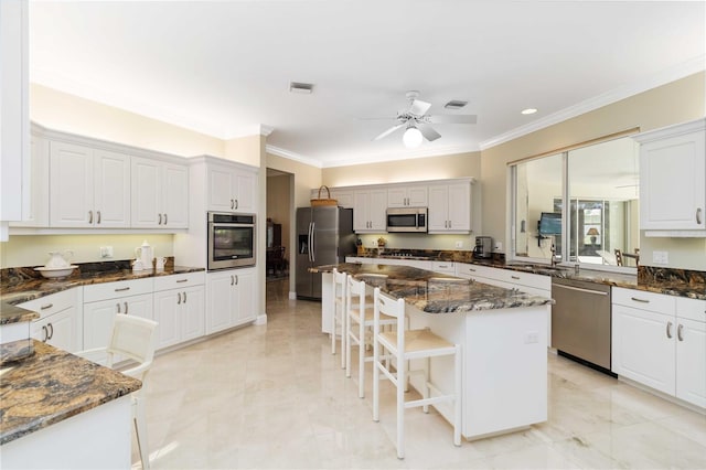 2067 Tocobaga Ln, Nokomis, FL 34275 - kitchen featuring appliances with stainless steel finishes, ornamental molding, white cabinetry, a kitchen breakfast bar, and a kitchen island