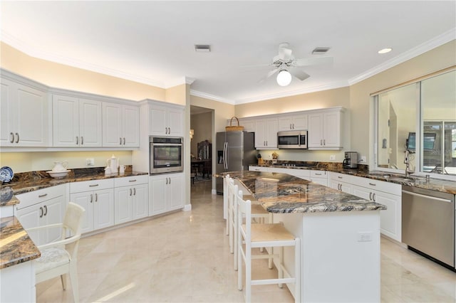 2067 Tocobaga Ln, Nokomis, FL 34275 - kitchen with stainless steel appliances, crown molding, ceiling fan, a sink, and dark stone countertops