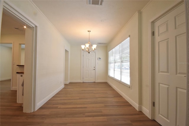 hallway with wood finished floors, a chandelier, and baseboards