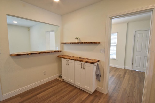 kitchen featuring butcher block counters, dark wood-style flooring, white cabinets, and baseboards
