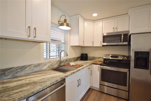 kitchen with appliances with stainless steel finishes, a sink, white cabinets, recessed lighting, and dark wood-style flooring