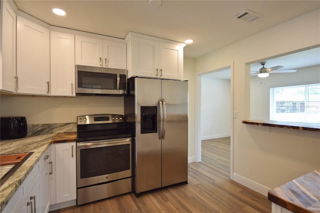 kitchen featuring stainless steel appliances, baseboards, white cabinets, light wood-type flooring, and recessed lighting