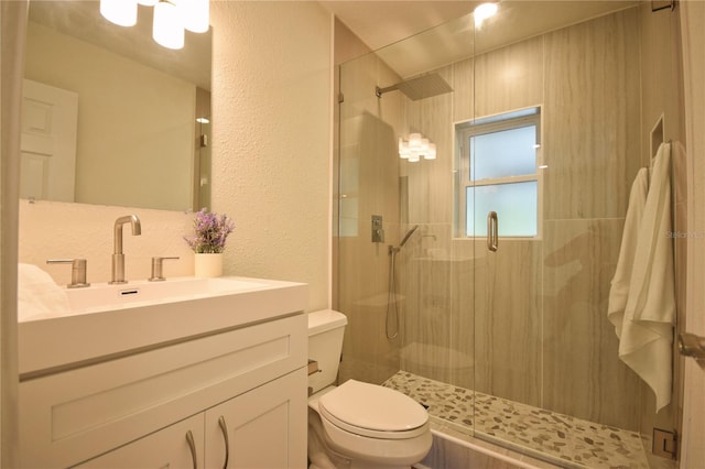 full bath featuring toilet, a stall shower, a textured wall, and vanity