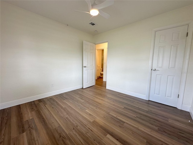 unfurnished bedroom featuring baseboards, dark wood-type flooring, and a ceiling fan