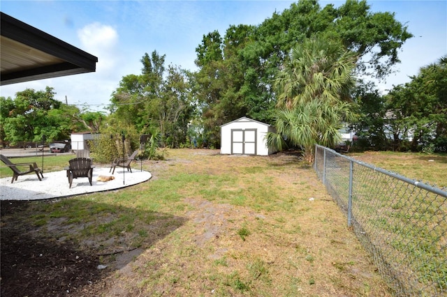 view of yard featuring a storage unit, an outbuilding, a fire pit, and a patio area
