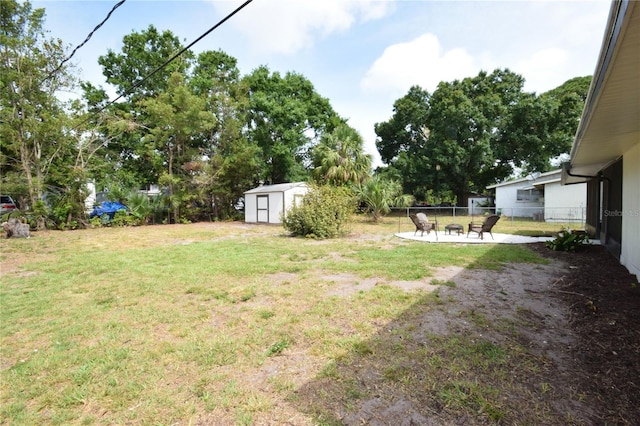 view of yard with a shed, a patio, an outbuilding, and a fire pit