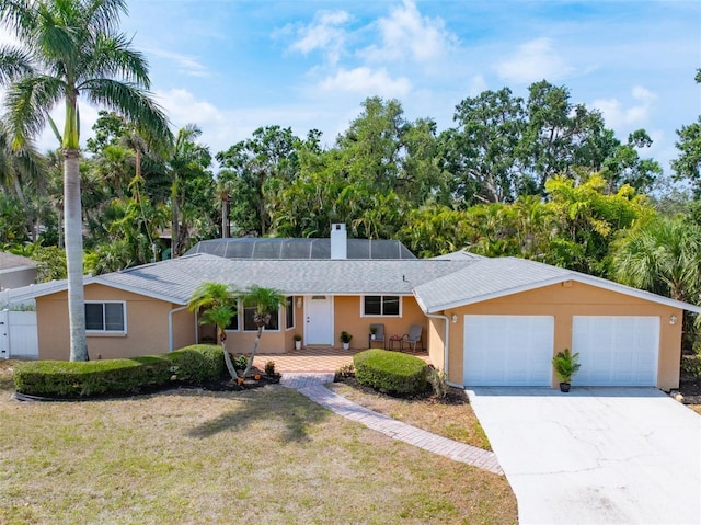 single story home with a garage, driveway, a front yard, and a chimney