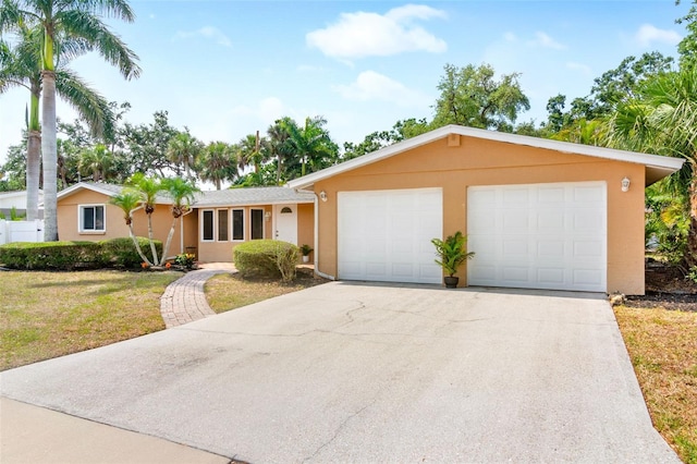 ranch-style home with driveway, stucco siding, a garage, and a front lawn