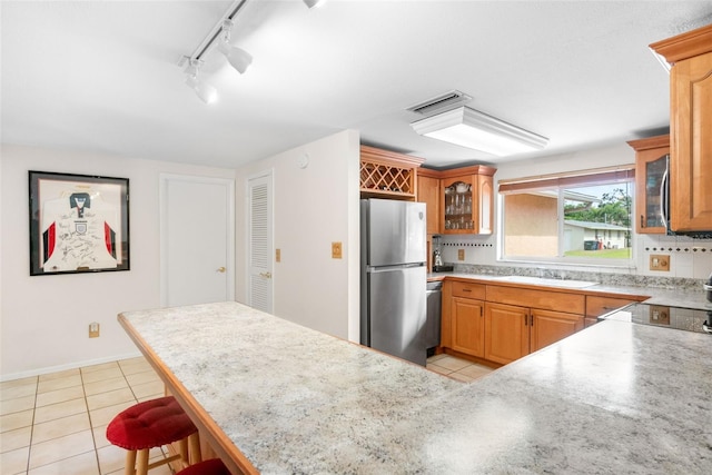 kitchen with stainless steel appliances, glass insert cabinets, a breakfast bar area, and light tile patterned flooring