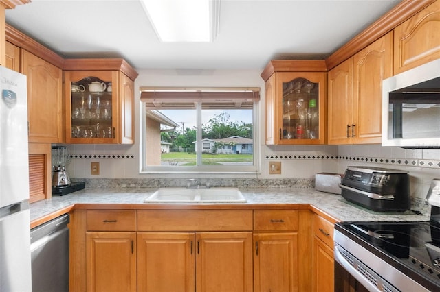 kitchen featuring stainless steel appliances, a sink, light countertops, and decorative backsplash