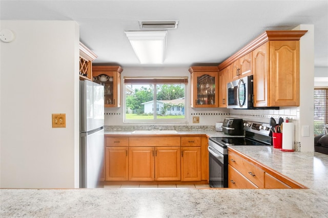 kitchen featuring stainless steel appliances, a sink, light countertops, and healthy amount of natural light