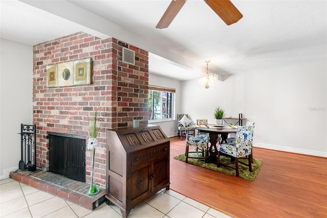 tiled dining area with a ceiling fan, a chandelier, baseboards, and a fireplace