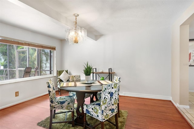 dining area with a chandelier, baseboards, and wood finished floors