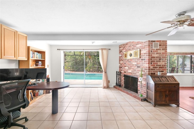 office featuring a fireplace, healthy amount of natural light, a ceiling fan, and light tile patterned floors