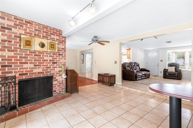 living area featuring track lighting, ceiling fan, light tile patterned floors, and a fireplace