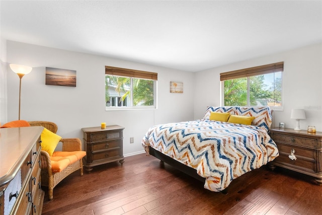 bedroom featuring multiple windows, dark wood-type flooring, and baseboards