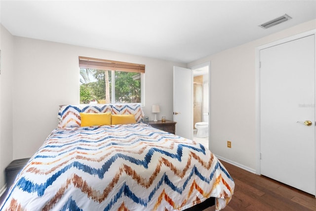 bedroom with wood finished floors, connected bathroom, and baseboards