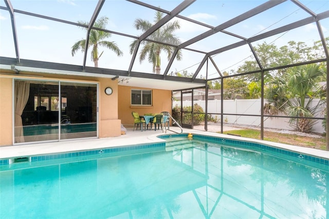 view of swimming pool with a patio area, glass enclosure, and fence