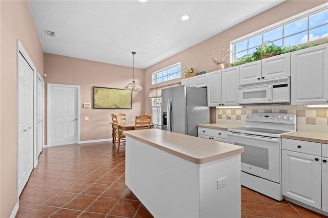 6764 Hickory Hammock Cir, Bradenton, FL 34202 - kitchen featuring white appliances, decorative backsplash, white cabinets, a kitchen island, and dark tile patterned floors
