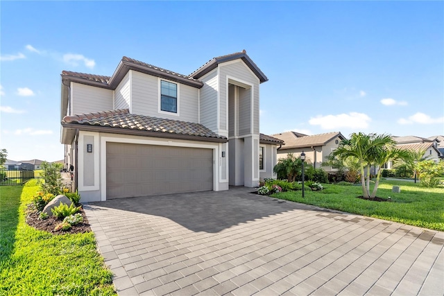 view of front of home with a tile roof, decorative driveway, a garage, and stucco siding