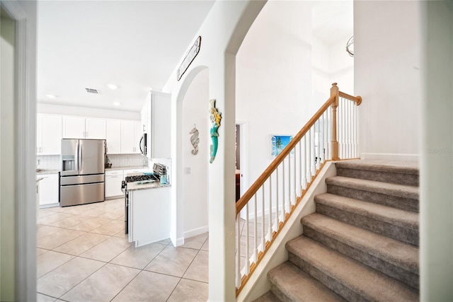 stairs featuring arched walkways, tile patterned floors, baseboards, and recessed lighting