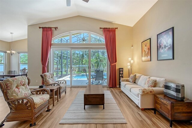 6605 38th Ln E, Sarasota, FL 34243 - living area with ceiling fan, vaulted ceiling, light wood-style flooring, and a chandelier