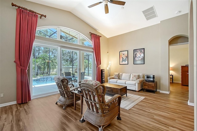 6605 38th Ln E, Sarasota, FL 34243 - living area with arched walkways, a ceiling fan, wood finished floors, baseboards, and high vaulted ceiling