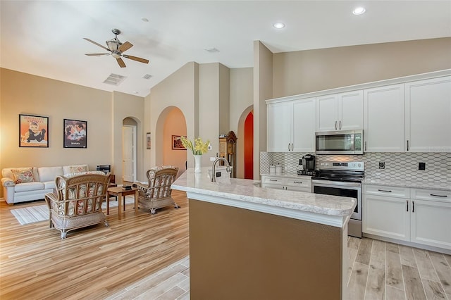 6605 38th Ln E, Sarasota, FL 34243 - kitchen featuring appliances with stainless steel finishes, arched walkways, high vaulted ceiling, a ceiling fan, and light wood-style floors