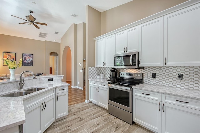 6605 38th Ln E, Sarasota, FL 34243 - kitchen with appliances with stainless steel finishes, arched walkways, a sink, ceiling fan, and decorative backsplash