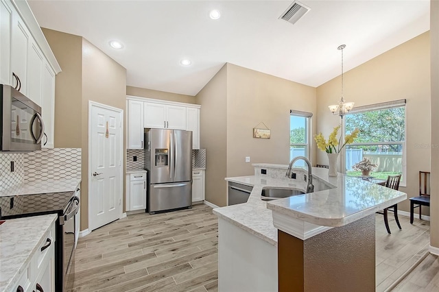 6605 38th Ln E, Sarasota, FL 34243 - kitchen featuring appliances with stainless steel finishes, a sink, decorative backsplash, light wood-style flooring, and high vaulted ceiling