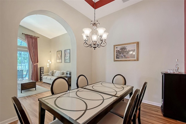 6605 38th Ln E, Sarasota, FL 34243 - dining space with arched walkways, wood finished floors, vaulted ceiling, a chandelier, and baseboards