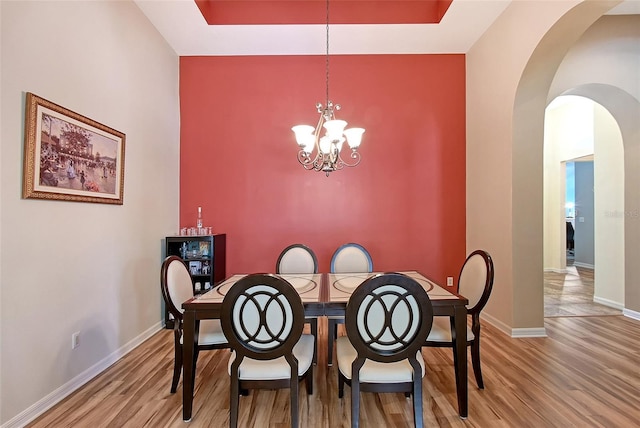 6605 38th Ln E, Sarasota, FL 34243 - dining room featuring wood finished floors, arched walkways, baseboards, and a chandelier