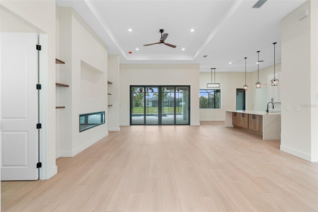 117 Marker Rd, Rotonda West, FL 33947 - unfurnished living room with ceiling fan, a raised ceiling, recessed lighting, light wood-style floors, and baseboards