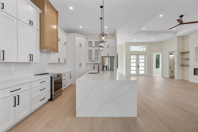 117 Marker Rd, Rotonda West, FL 33947 - kitchen with stainless steel appliances, light wood-style floors, decorative backsplash, decorative light fixtures, and a kitchen island with sink