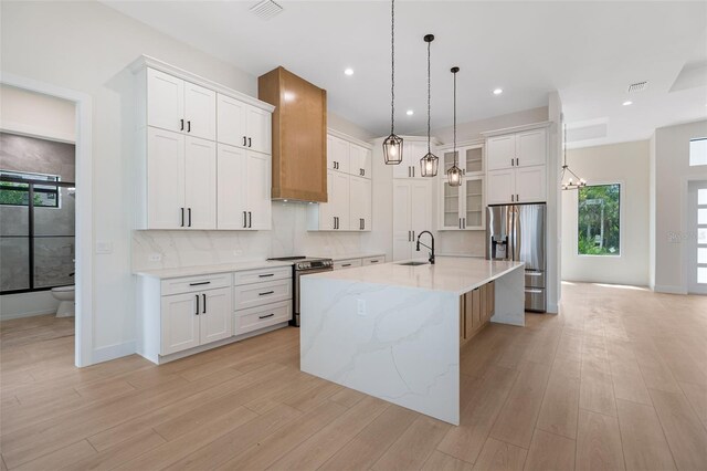 117 Marker Rd, Rotonda West, FL 33947 - kitchen with stainless steel appliances, white cabinetry, a large island with sink, light wood-style floors, and recessed lighting