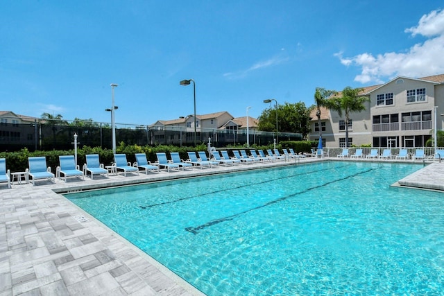 community pool featuring fence, a patio area, and a residential view