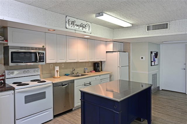 2901 26th St W Unit 312, Bradenton, FL 34205 - kitchen with stainless steel appliances, light wood-type flooring, a sink, white cabinets, and a center island