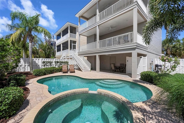 view of pool featuring a fenced backyard, ceiling fan, a pool with connected hot tub, and stairway