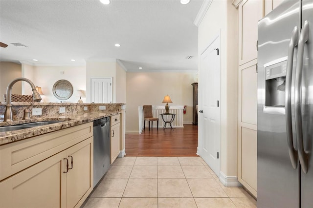 kitchen featuring stainless steel appliances, a sink, ornamental molding, light tile patterned flooring, and light stone counters