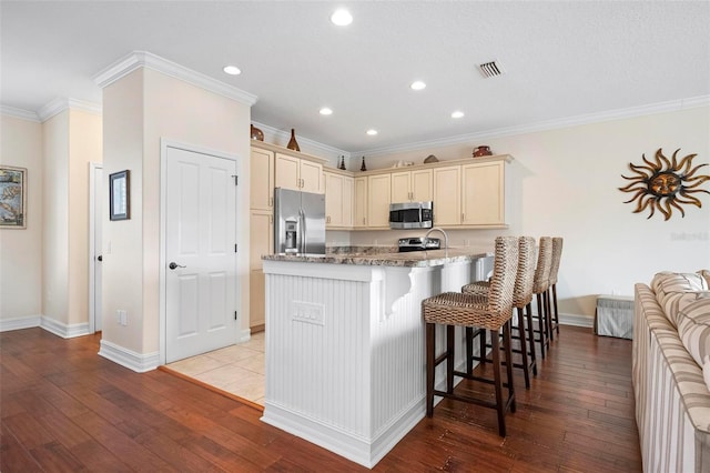 kitchen with stainless steel appliances, a peninsula, ornamental molding, recessed lighting, and a kitchen bar