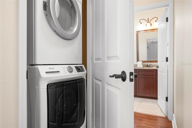 laundry area featuring stacked washer / drying machine and light wood-style floors