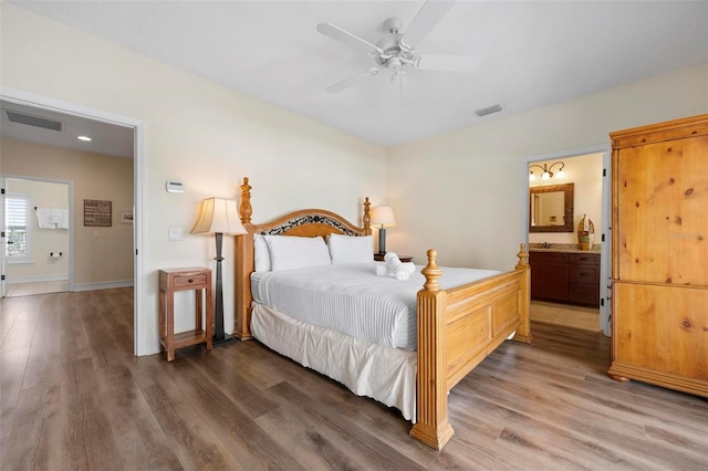 bedroom with light wood finished floors, baseboards, ensuite bath, and a ceiling fan