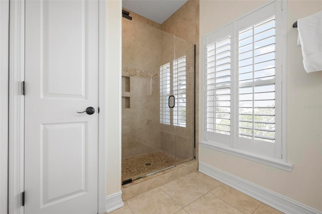 bathroom with tile patterned floors, a shower stall, and baseboards