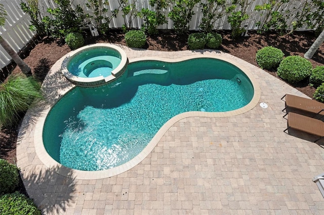 view of pool featuring a pool with connected hot tub, a patio area, and fence